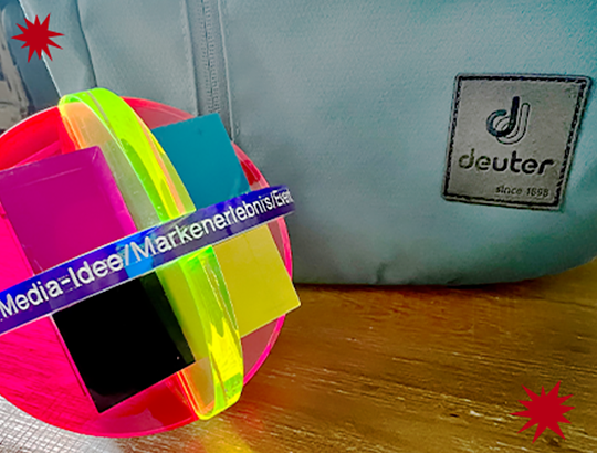 Ein Deuter Rucksack im Hintergrund, davor steht der Deutsche Media Preis von W+V