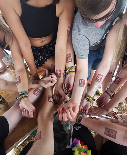 Bild zeigt ein großes Team von Spielern der Festival-Hunt auf dem Open Flair in Eschwege aus der Vogelperspektive, im Zentrum hauptsächlich die Arme mit temporären Logo-Tattoos
