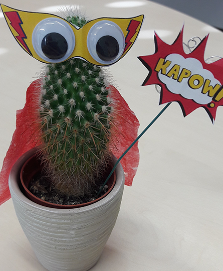Ein Kaktus, der mit Hilfe von Papierbastelei und Wackelaugen zum Superhelden umdekoriert wurde