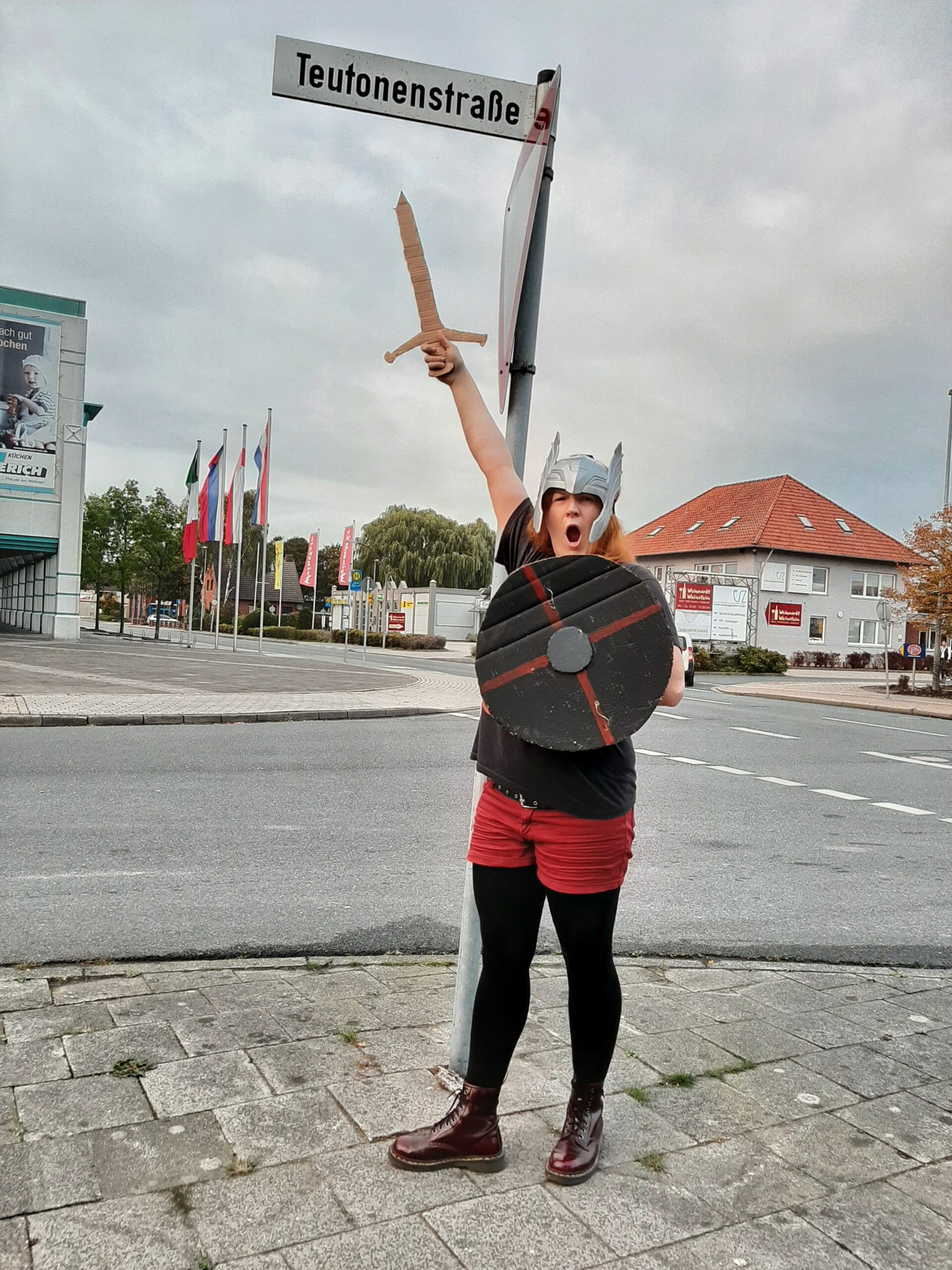 Eine Teutonin in der Teutonenstraße Teilnehmerin einer Scavenger Hunt als Teutonin verkleidet unter dem Straßenschild der Teutonenstraße